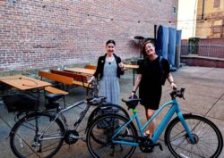 evolvers Mae Catino and Breen Masciotra happily stand behind their two-wheeled work commute vehicles.